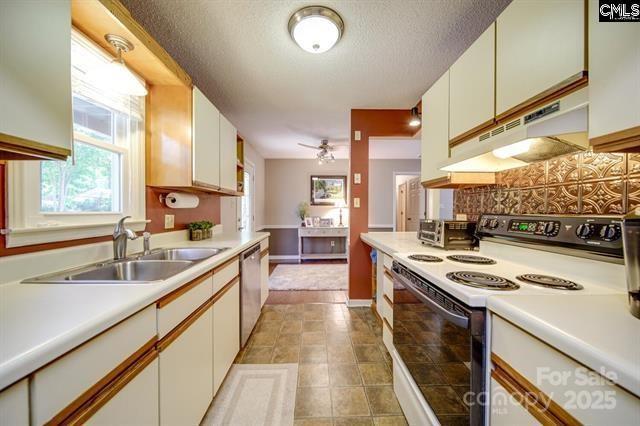 kitchen featuring white electric range oven, light countertops, white cabinetry, a sink, and under cabinet range hood