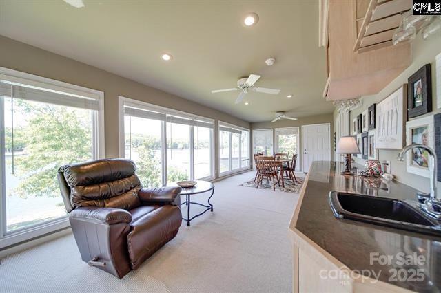 kitchen featuring light carpet, dark countertops, open floor plan, a sink, and recessed lighting