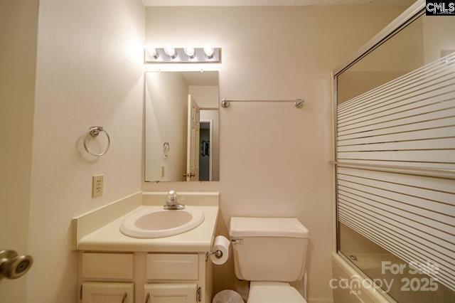 bathroom with vanity, toilet, and bath / shower combo with glass door