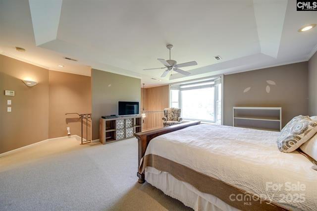 carpeted bedroom featuring recessed lighting, a ceiling fan, visible vents, baseboards, and a tray ceiling