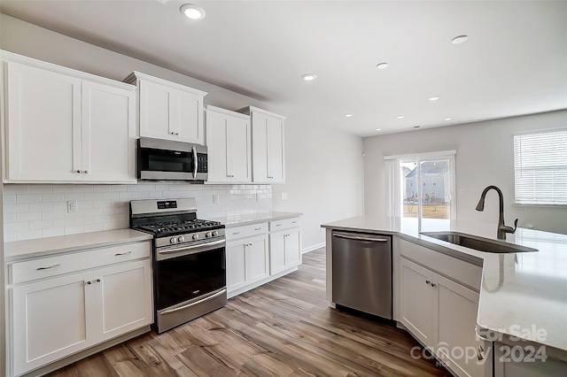 kitchen with light hardwood / wood-style floors, white cabinetry, and stainless steel appliances