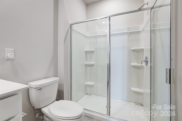 bathroom featuring vanity, toilet, and a shower with door