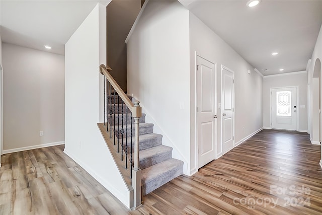 foyer entrance with crown molding and light wood-type flooring