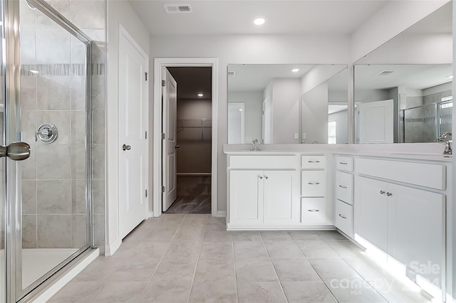 bathroom featuring tile patterned flooring, vanity, and a shower with door