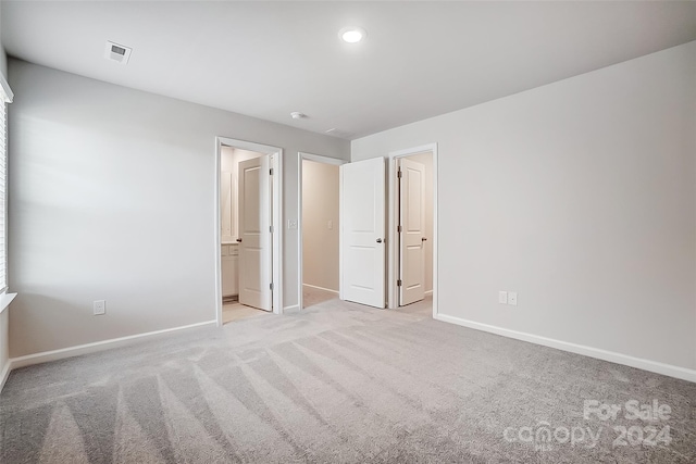 unfurnished bedroom with light carpet and ensuite bath