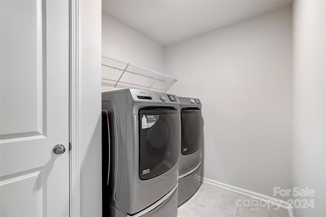 clothes washing area featuring washer and clothes dryer and light tile patterned floors