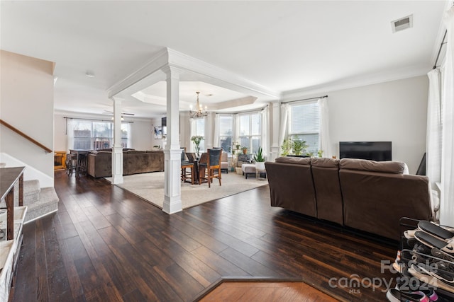 living room with dark hardwood / wood-style flooring, decorative columns, an inviting chandelier, and ornamental molding