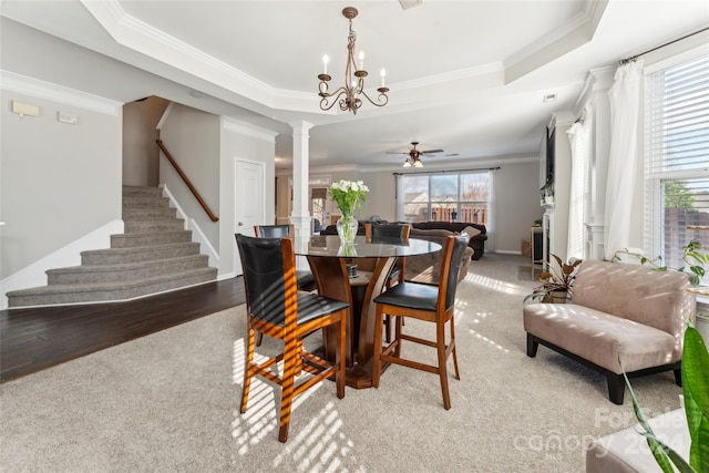 dining room featuring hardwood / wood-style flooring, ceiling fan with notable chandelier, a raised ceiling, and ornamental molding