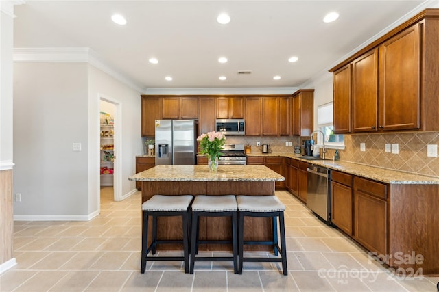 kitchen with sink, light stone countertops, tasteful backsplash, a kitchen island, and stainless steel appliances