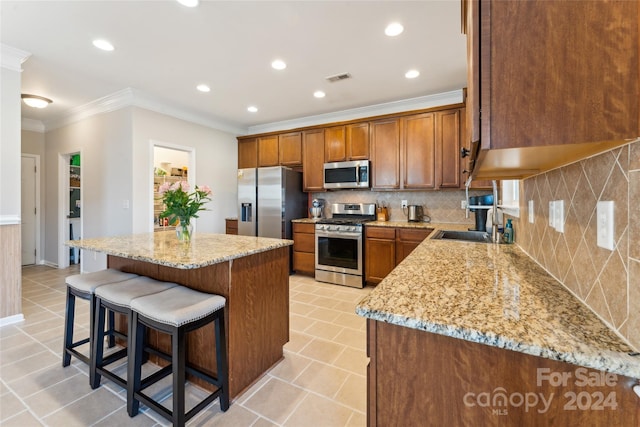 kitchen with backsplash, light stone countertops, a center island, and appliances with stainless steel finishes