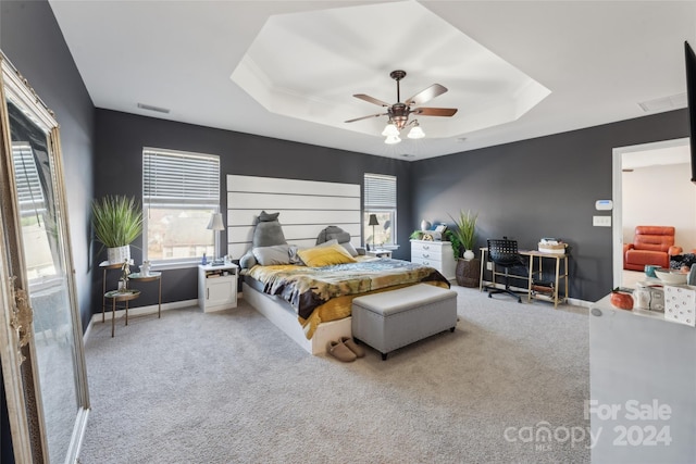 bedroom with light carpet, a raised ceiling, and ceiling fan