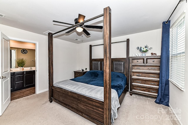 bedroom with ensuite bathroom, ceiling fan, and light colored carpet