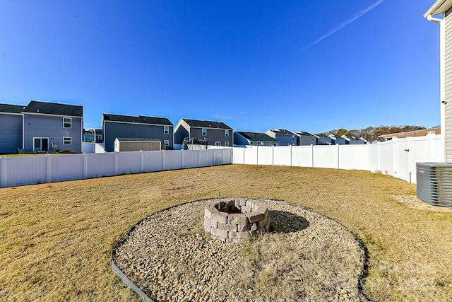 view of yard with central air condition unit and an outdoor fire pit