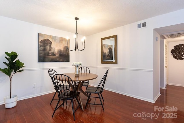 dining space with dark wood-type flooring and an inviting chandelier