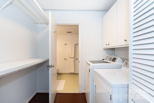 clothes washing area featuring cabinets and separate washer and dryer