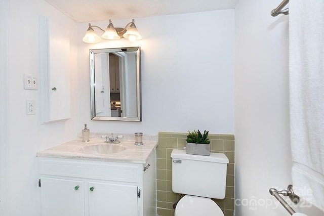 bathroom with tile walls, toilet, and vanity