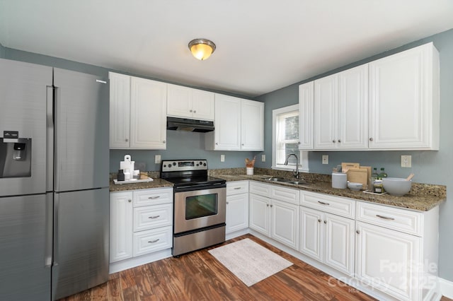 kitchen with under cabinet range hood, white cabinetry, appliances with stainless steel finishes, dark wood-style floors, and dark stone countertops