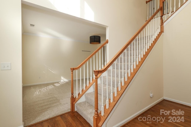 stairs with crown molding and wood-type flooring