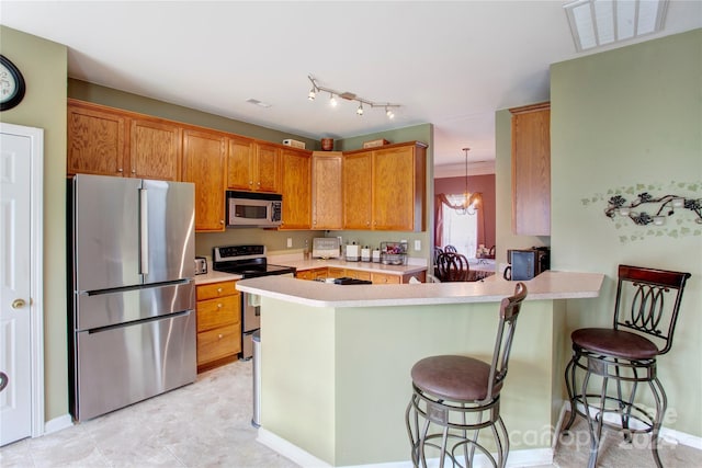 kitchen with an inviting chandelier, a kitchen breakfast bar, decorative light fixtures, kitchen peninsula, and stainless steel appliances