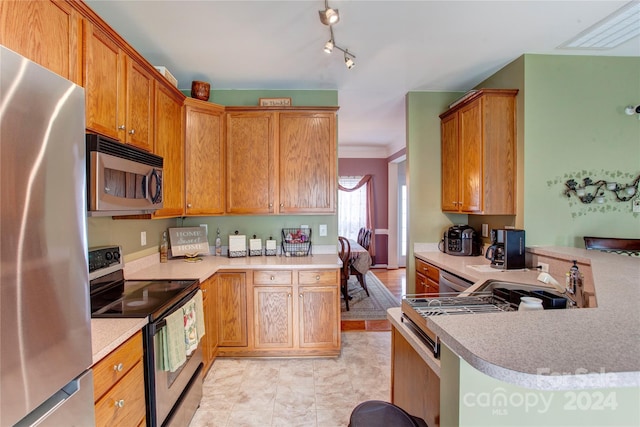 kitchen with kitchen peninsula, crown molding, light tile patterned floors, and stainless steel appliances