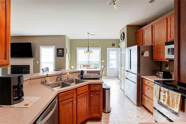 kitchen with rail lighting, hanging light fixtures, sink, appliances with stainless steel finishes, and a chandelier