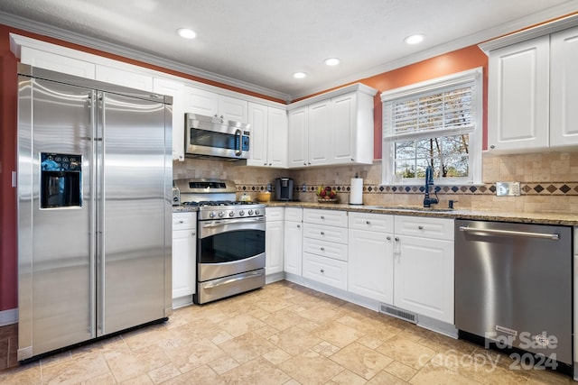 kitchen featuring sink, light stone counters, appliances with stainless steel finishes, white cabinets, and ornamental molding