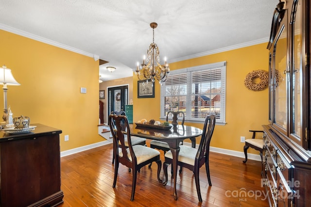 dining room with a textured ceiling, ornamental molding, dark hardwood / wood-style floors, and a notable chandelier