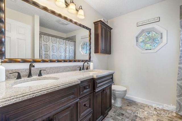 bathroom featuring a textured ceiling, vanity, and toilet