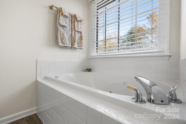 bathroom with hardwood / wood-style floors and tiled bath