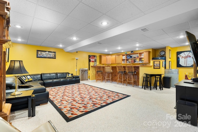 living room featuring a drop ceiling, light carpet, and bar