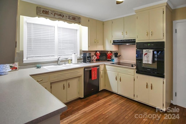 kitchen with crown molding, sink, black appliances, cream cabinets, and hardwood / wood-style floors