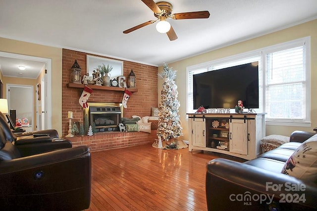 living room featuring ceiling fan, wood-type flooring, and a brick fireplace