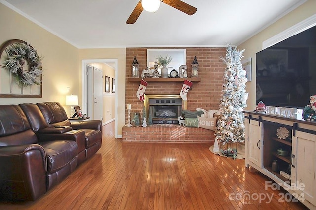 living room featuring a fireplace, wood-type flooring, ceiling fan, and crown molding