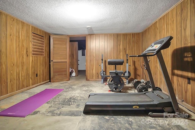 workout room with wooden walls and a textured ceiling