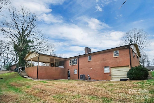 rear view of house featuring a lawn, central AC, and a garage