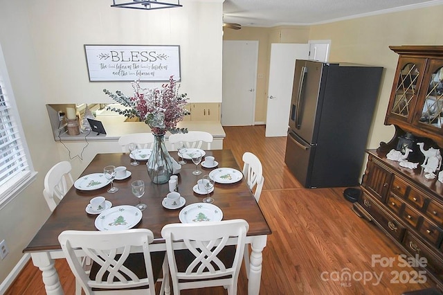 dining room with baseboards, wood finished floors, and crown molding