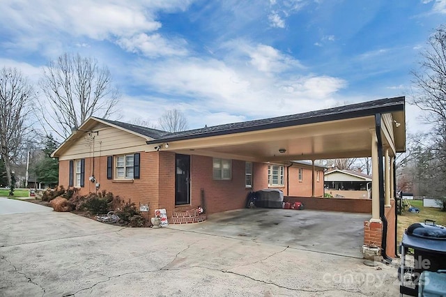 view of side of home with an attached carport, concrete driveway, brick siding, and entry steps