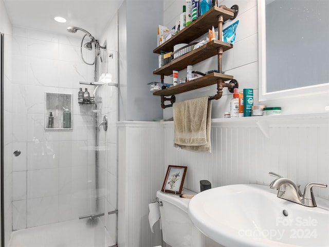 bathroom featuring toilet, a shower with shower door, and sink