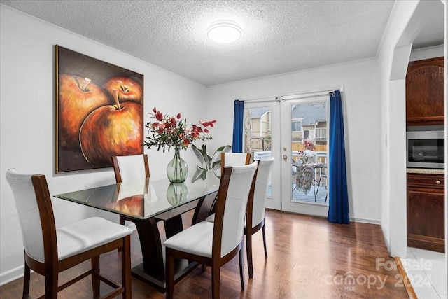 dining room featuring french doors, ornamental molding, a textured ceiling, and hardwood / wood-style flooring