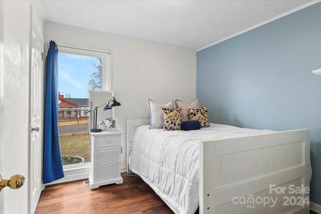 bedroom featuring a textured ceiling, crown molding, and dark hardwood / wood-style floors