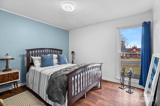 bedroom with multiple windows, crown molding, a textured ceiling, and hardwood / wood-style flooring