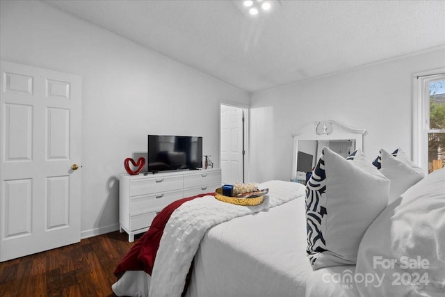 bedroom featuring a textured ceiling, dark hardwood / wood-style flooring, and vaulted ceiling