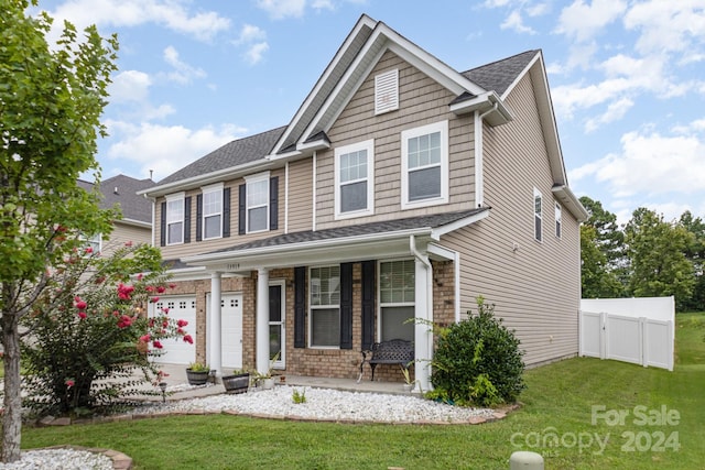 craftsman inspired home featuring covered porch, a garage, and a front yard