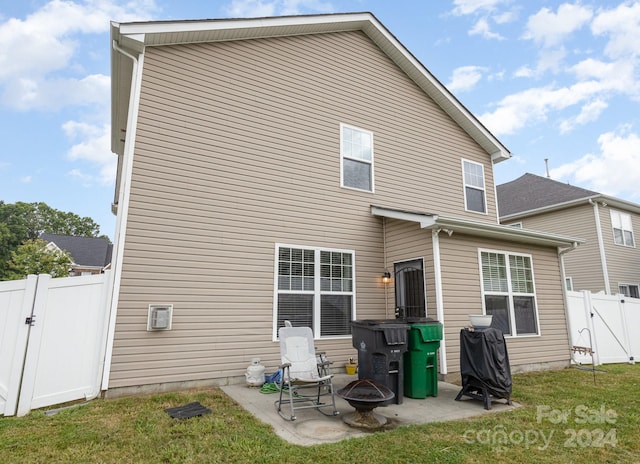 back of house featuring a lawn, a fire pit, and a patio area