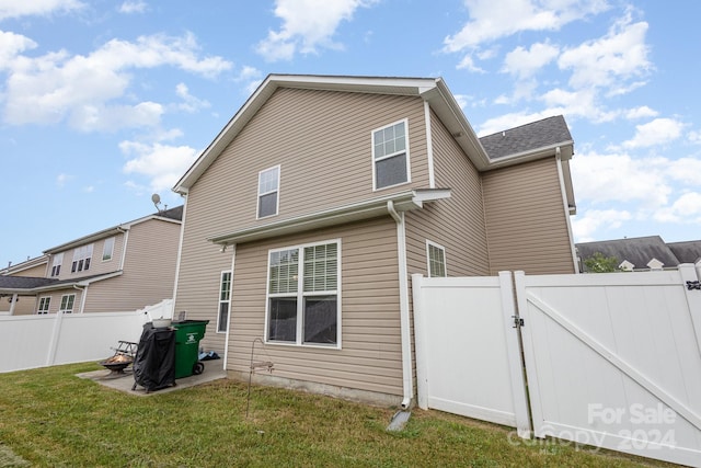 rear view of property featuring a lawn and a patio