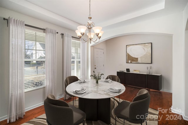 dining space featuring a healthy amount of sunlight, dark hardwood / wood-style flooring, and an inviting chandelier