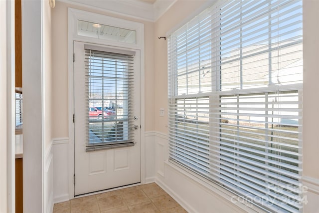 doorway to outside with crown molding, plenty of natural light, and light tile patterned floors