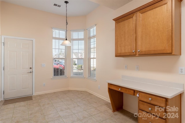 interior space with light tile patterned floors, built in desk, and hanging light fixtures