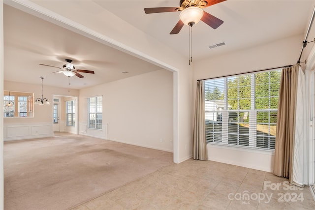 carpeted empty room featuring a wealth of natural light and a chandelier