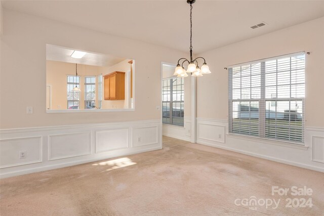 unfurnished dining area with light carpet and a notable chandelier